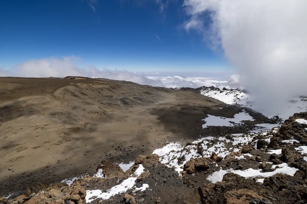 Panoramic view of mount kilimanjaro volcanic crater landscape with snow and clouds at high altitude