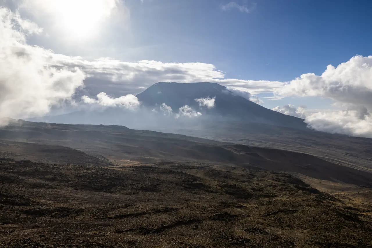 Scenic view of mount kilimanjaro peak with volcanic landscape and clouds under bright sunny sky