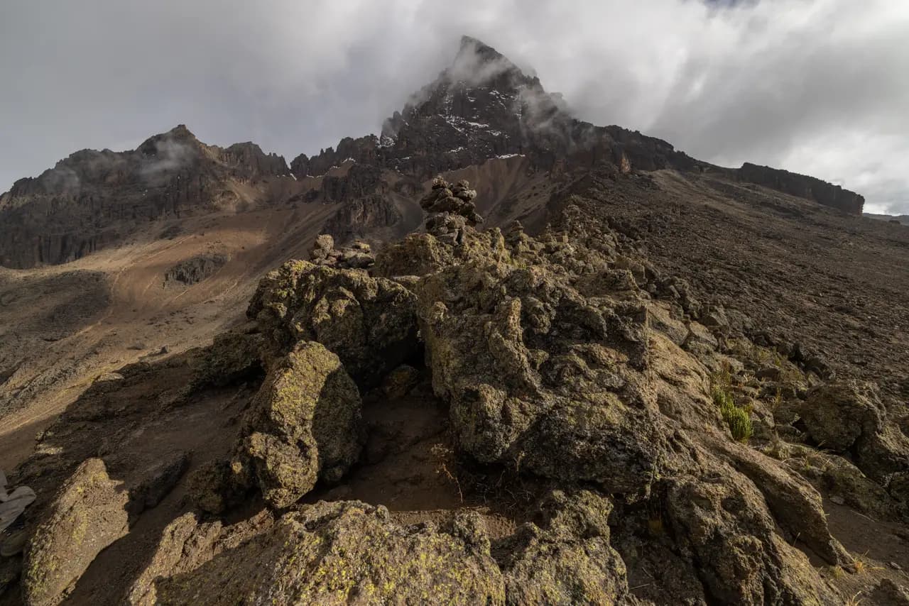 Volcanic eruption with steam plume rising from rocky mountain landscape