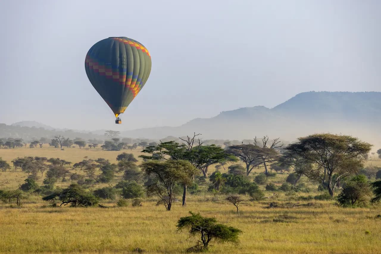 Hot air balloon flying over the african savanna landscape during a morning safari adventure